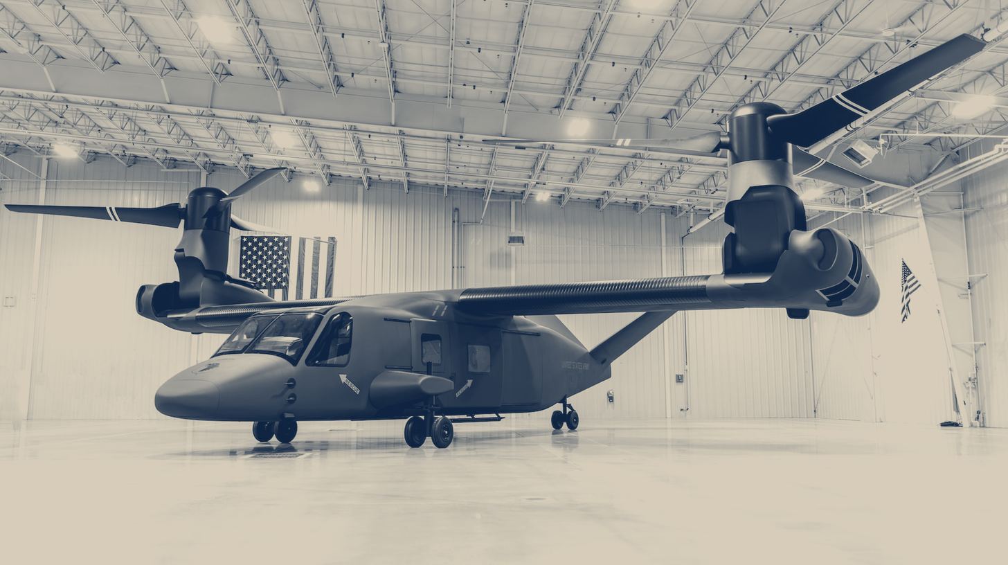 Two-tone Bell photo of the full-size MV-75 Cheyenne II mock-up, not a flying aircraft, parked in a hangar under a U.S. flag.