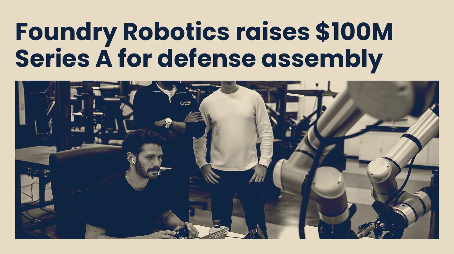 Foundry Robotics engineers work at a computer beside robotic arms on the company's factory floor in Emeryville, California, in navy and sand tones.