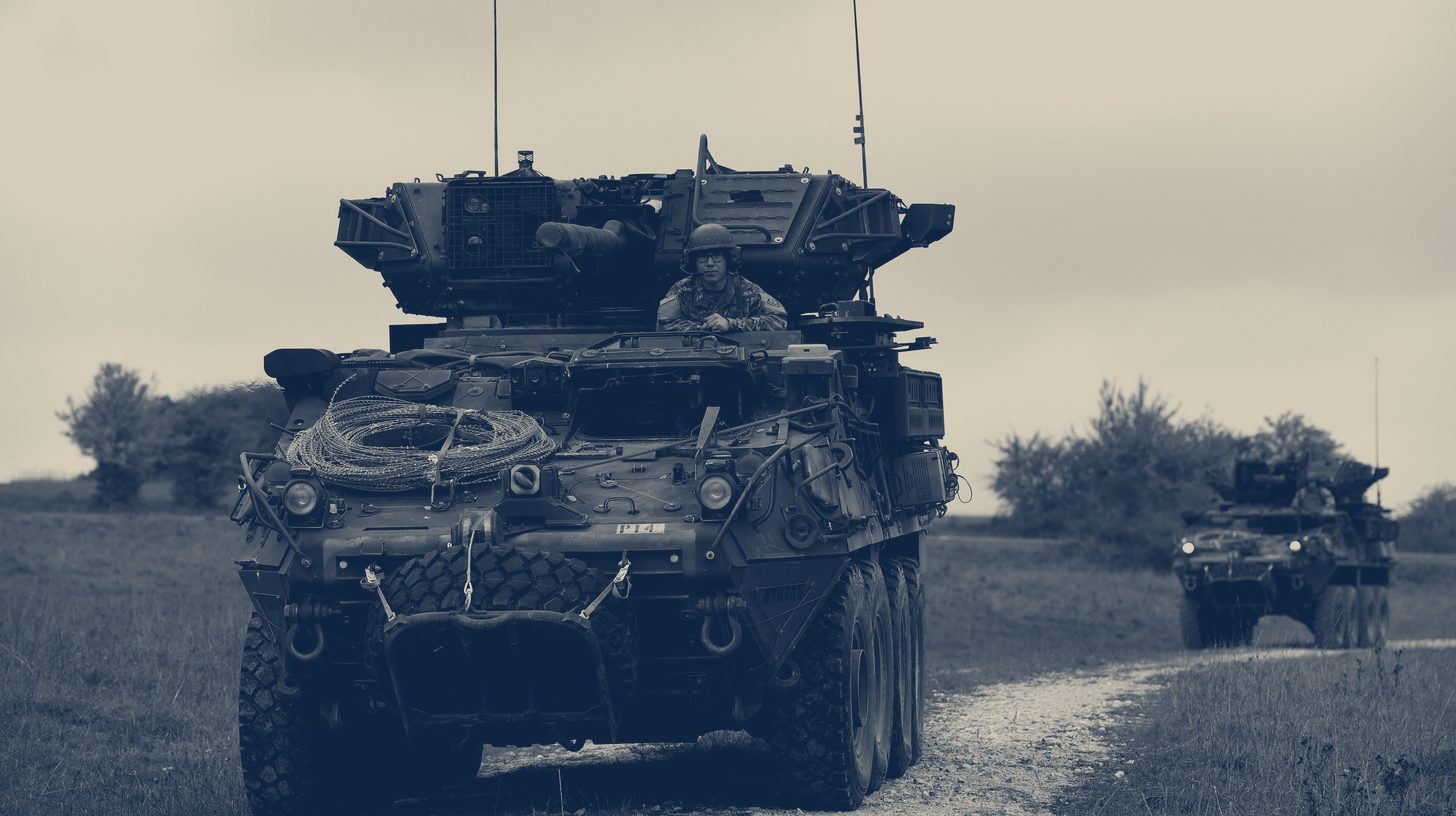 Two-tone U.S. Army photo of an M1296 Stryker Dragoon driving on a training area road, one of the vehicles that hosts PERCH 2.0, not the Wolf XM30.