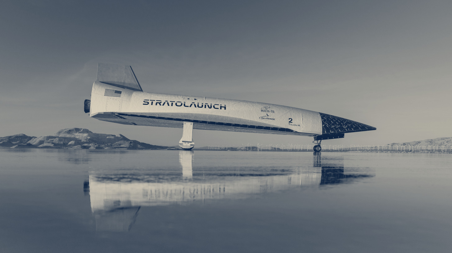 Two-tone Stratolaunch photo of the Talon-A hypersonic test vehicle on a dry lakebed, reflected in a sheet of water.