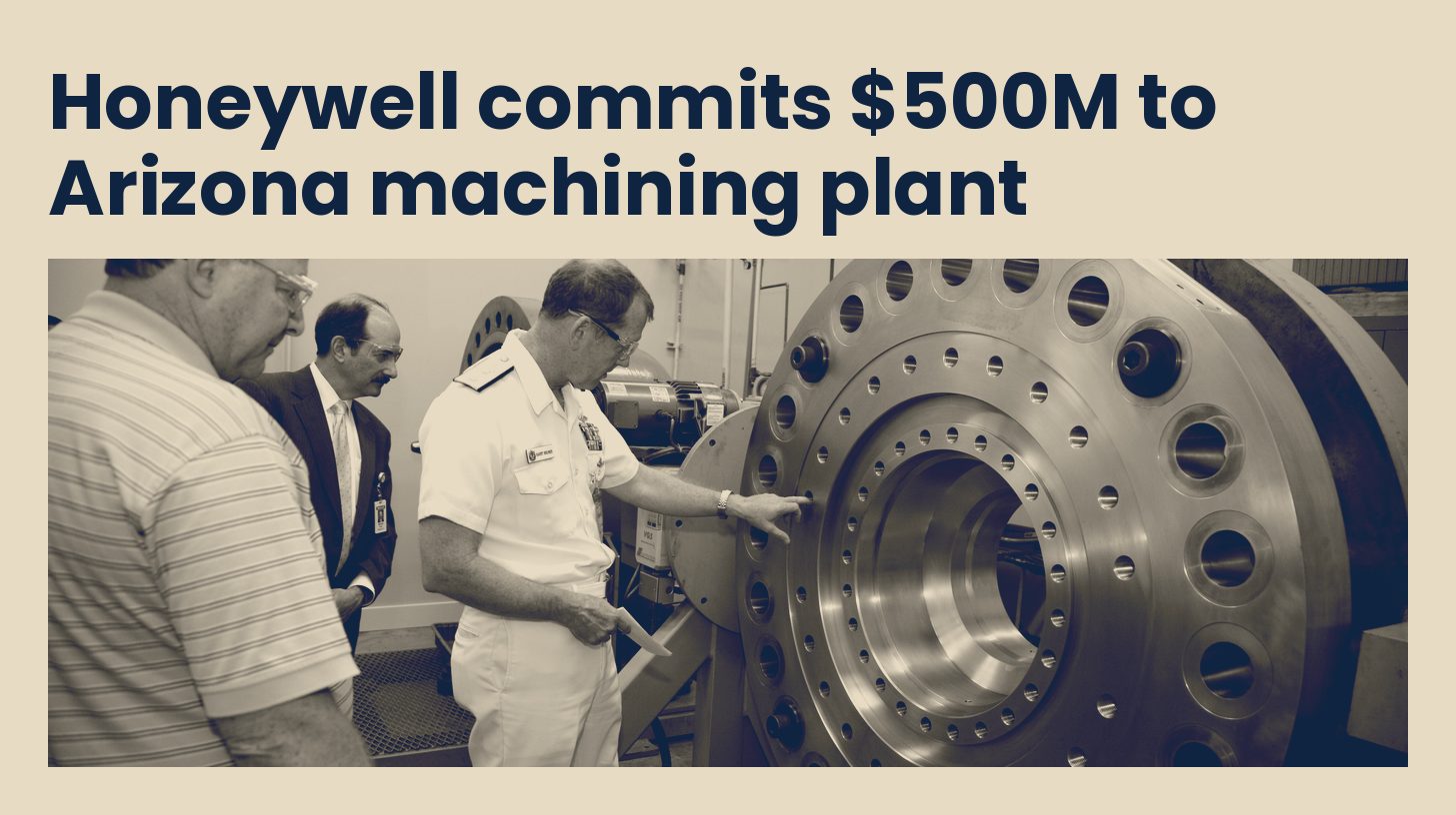 U.S. Navy visitors and Honeywell staff look over a large machined ring on the shop floor of Honeywell's Tempe, Arizona campus in 2010, in navy and sand tones.