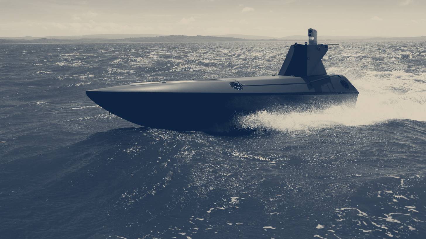 Two-tone Kraken Technology Group photo of a K3 Scout uncrewed surface vessel running at speed in coastal waters.