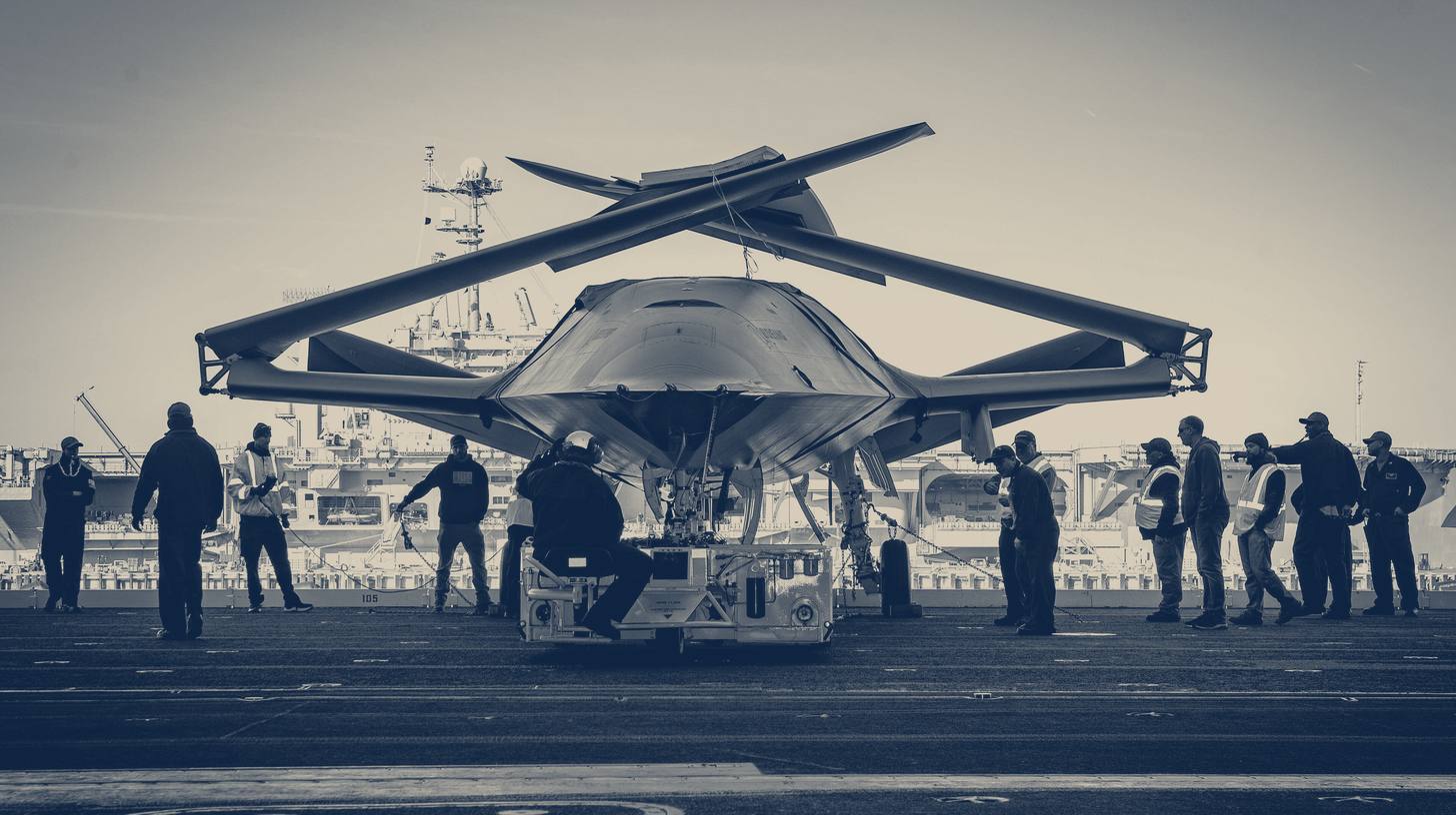 Two-tone 2021 U.S. Navy photo of sailors and Boeing staff moving an MQ-25 drone on the deck of USS George H.W. Bush, not USS Ronald Reagan.