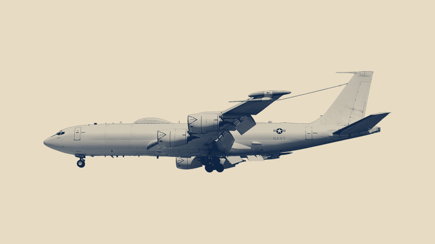 Two-tone photo of a U.S. Navy E-6B Mercury, the TACAMO aircraft the E-130J replaces, in flight at RIAT 2018, on a plain sand background.