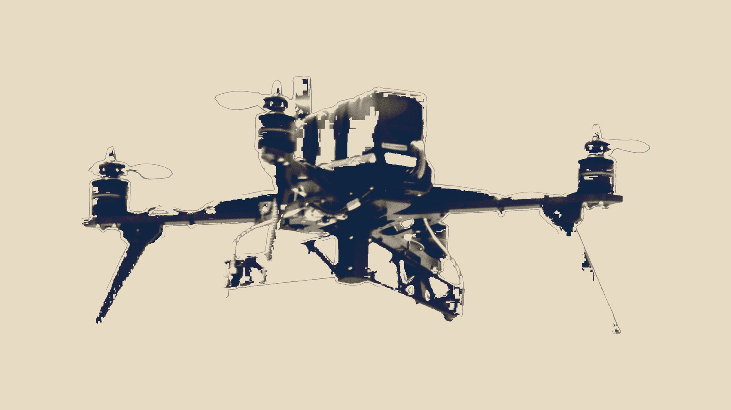 Matte-black Swarm Kiwi quadcopter with underside dropper hardpoints, isolated on a plain sand field.