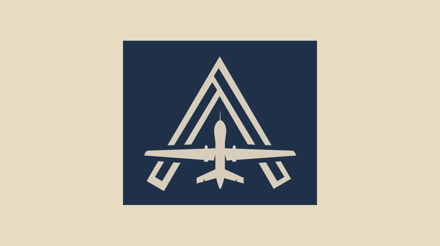 Two-tone version of the official Autonomous Warfare Command emblem mark, a drone inside a stylized letter A, as a navy panel on a plain sand background.