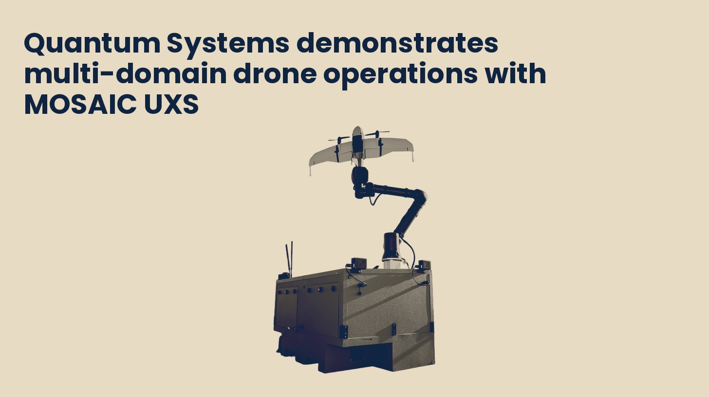 A Quantum Systems Twister fixed-wing drone held on a robotic arm atop a ruggedized launch container, isolated on a plain sand background.