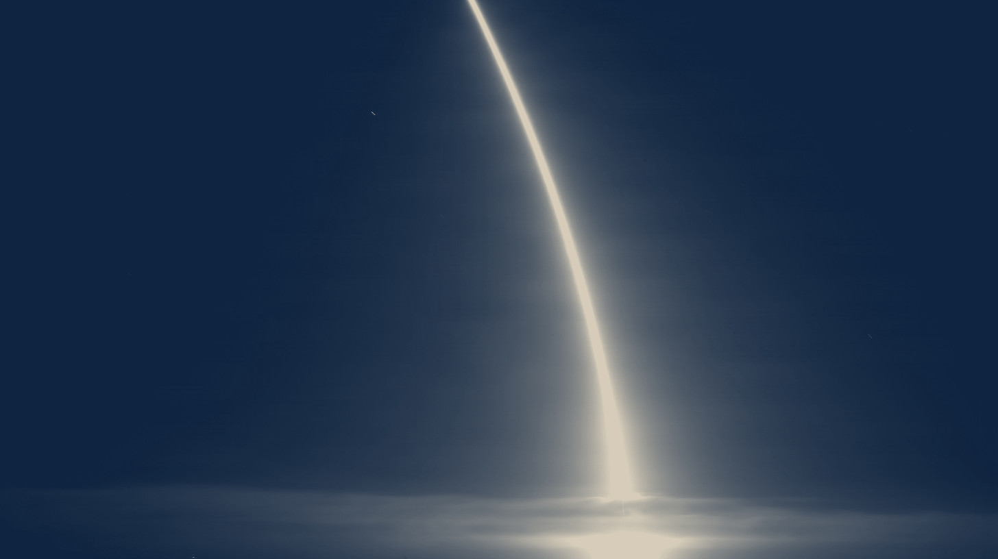 Two-tone U.S. Space Force long-exposure photo of a Falcon 9 Starlink launch arc over Vandenberg, a stand-in for SpaceX quarterly results.