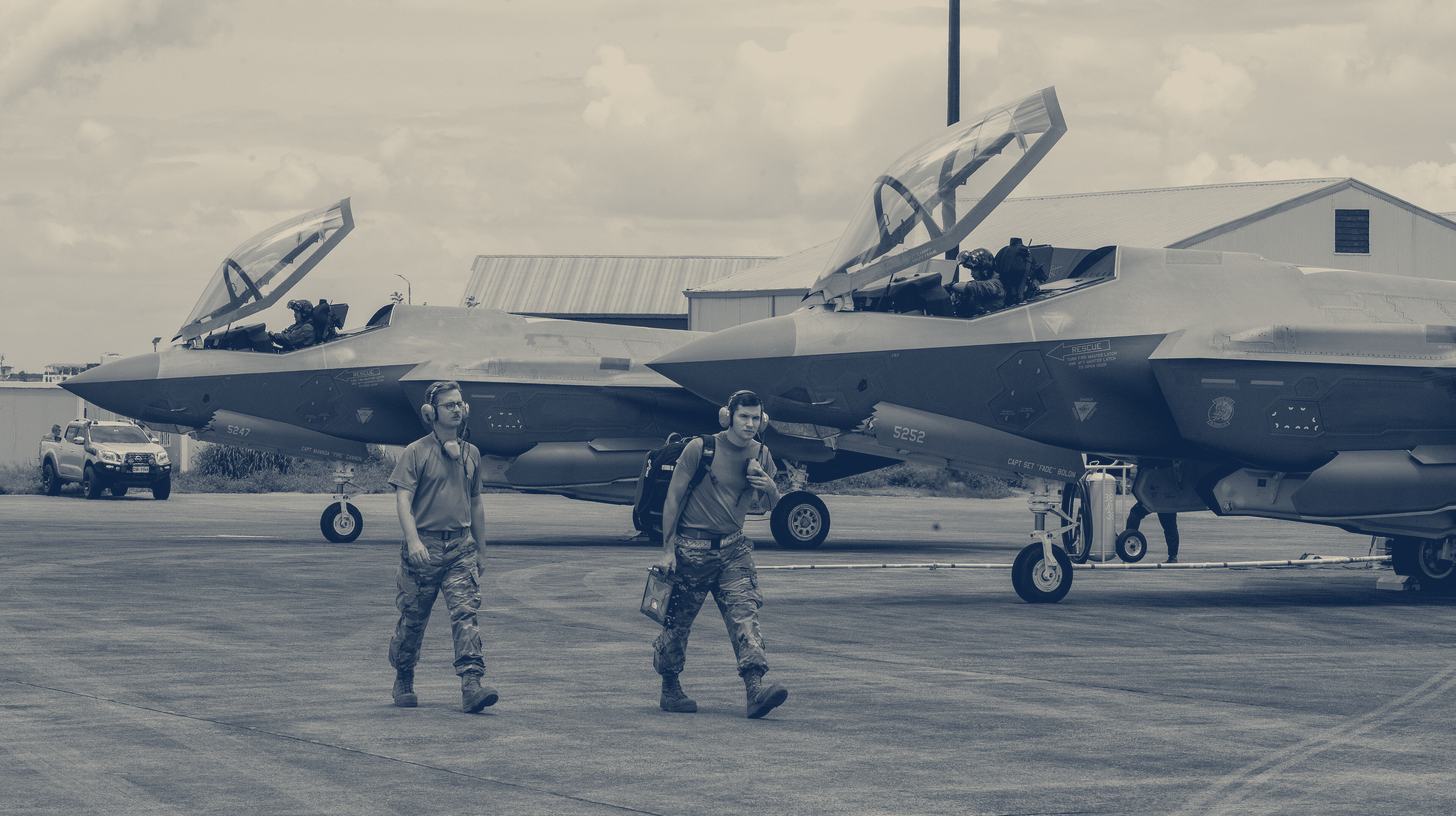 Two-tone U.S. Air Force photo of two crew members walking past parked F-35A fighters during Cope Thunder 25-2.