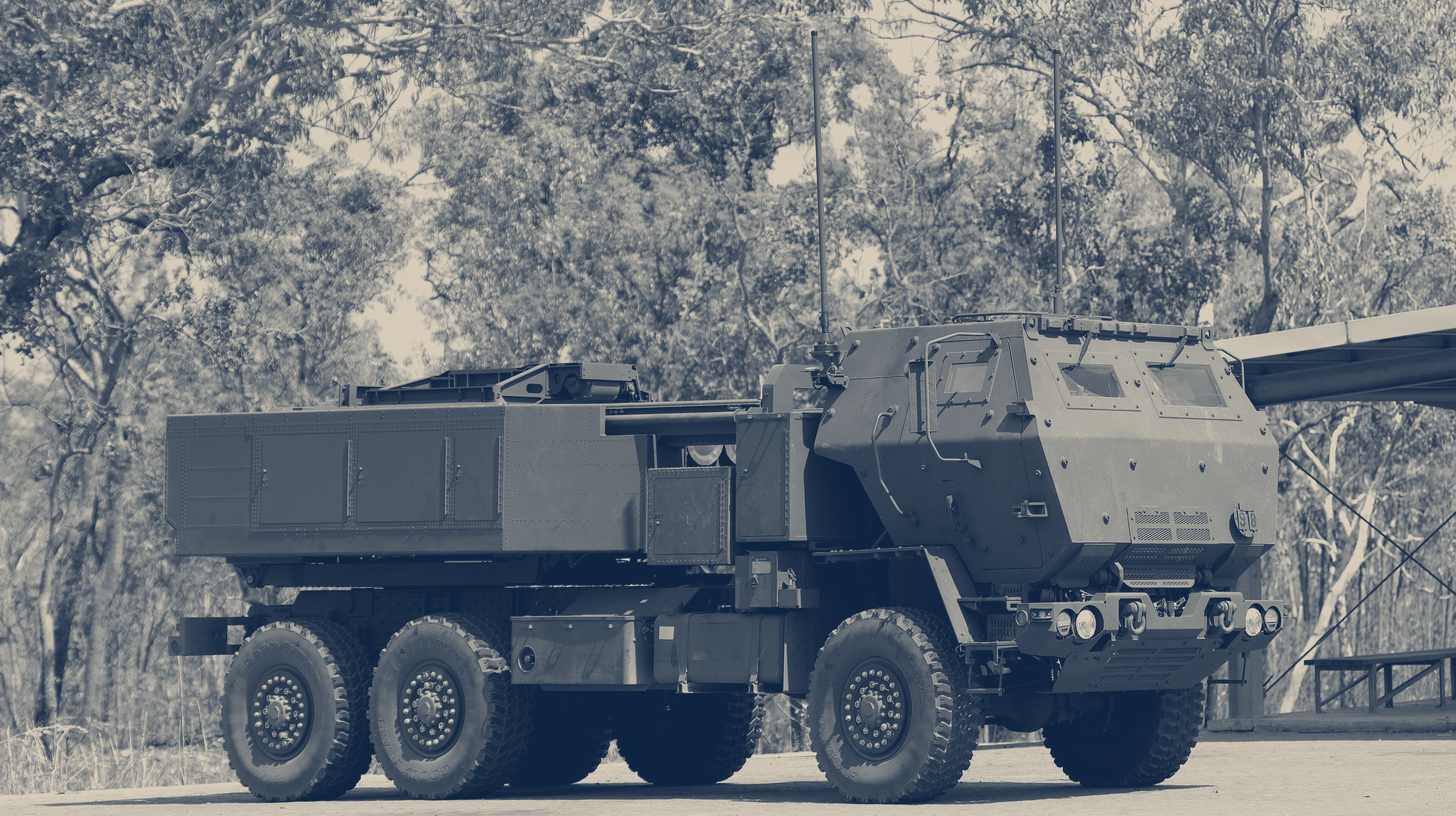 Two-tone U.S. Army photo of an Australian Army HIMARS launcher parked under trees at Mount Bundey, Australia.